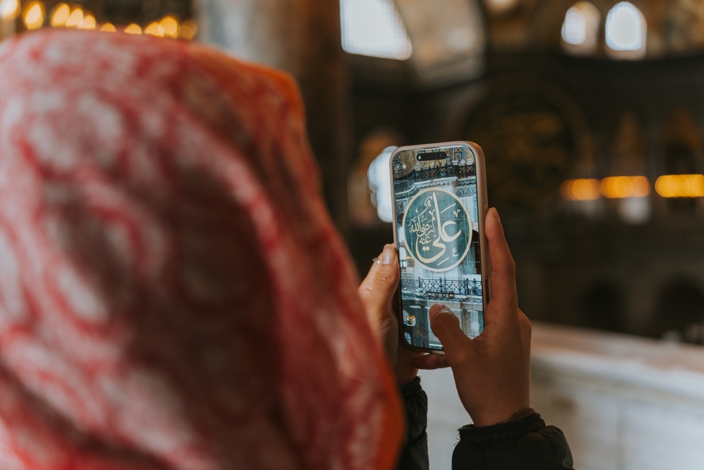 Visitor using smartphone inside Hagia Sophia to follow an audio guide while exploring the historic interior