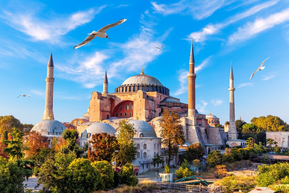 Hagia Sophia exterior view in Istanbul with large dome, minarets, and visitor entrance area at sunset